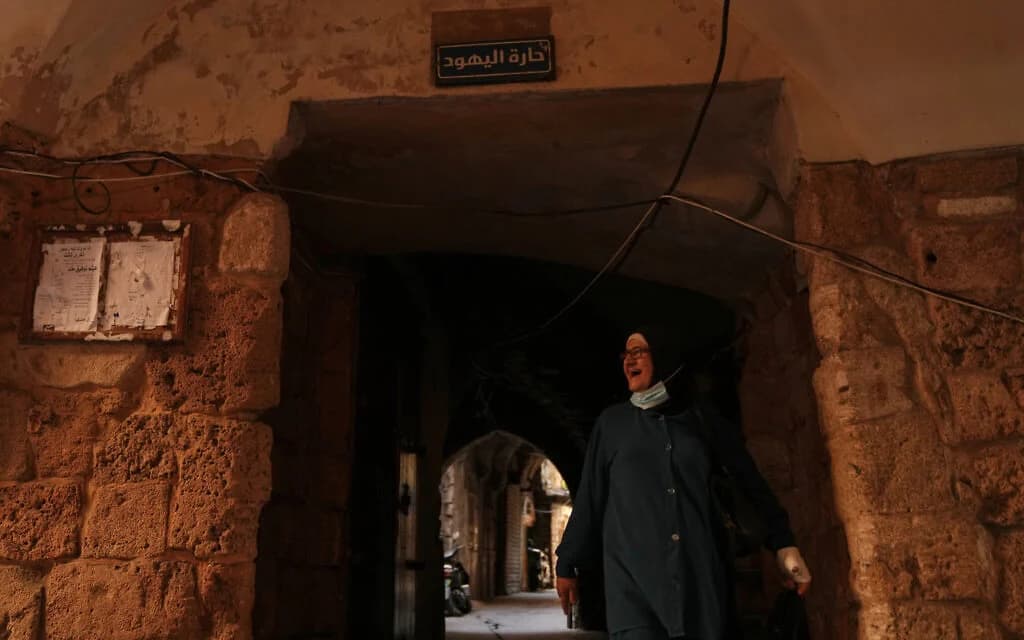 A woman walks beneath a sign reading 'Jewish Quarter' in the old city of Sidon, southern Lebanon